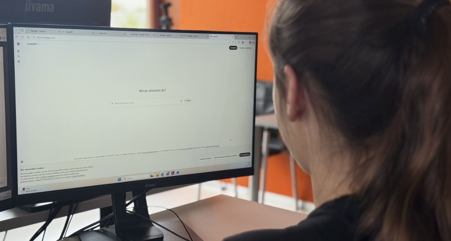 Eine Person sitzt vor einem Bildschirm auf dem eine KI aufgerufen wurde. 